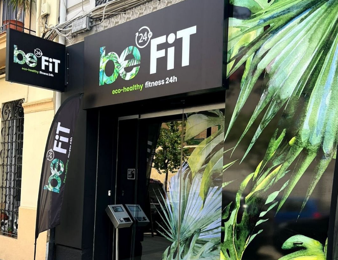 Entrada de be24FIT Valencia con su rótulo verde y blanco y decoración de hojas