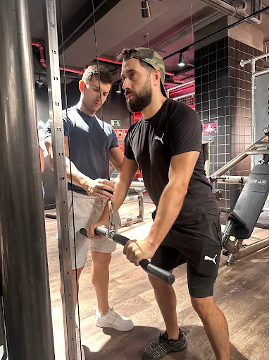 Sergio guiando a un cliente en un ejercicio de polea